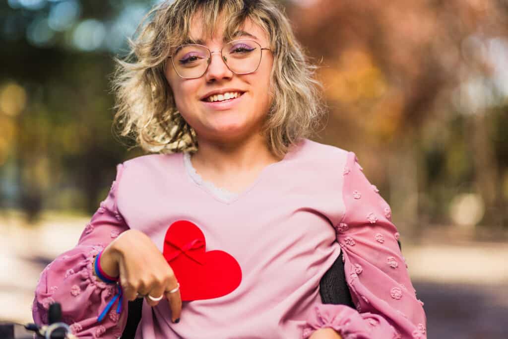 smiling woman with pink blouse holding red heart